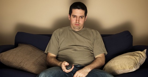 Bored, overweight man sits on the sofa